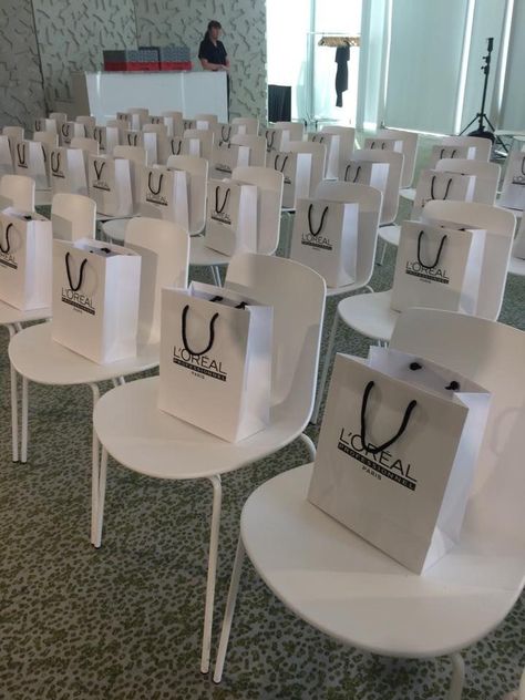 Simple and Minimalistic corporate event chair arrangement with souvenir bags Grand Opening Goodie Bags, Fashion Show Gift Bags Ideas, Event Goodie Bags, Beauty Masterclass Event, Makeup Event Ideas, Work Event Decor, Corporate Goodie Bags, Makeup Launch Party Ideas, Makeup Launch Event