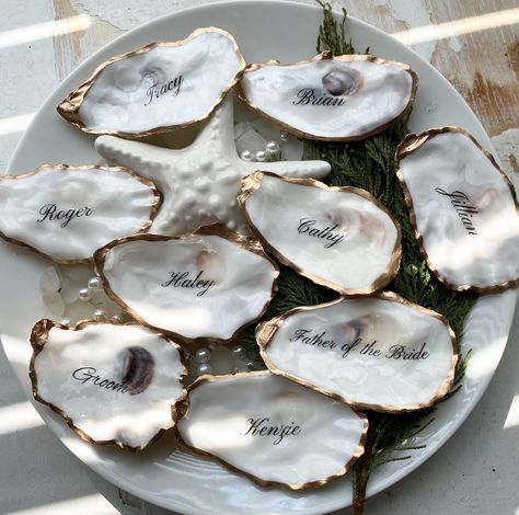 Welcome to our exclusive collection of personalized oyster shell place cards, designed to add a touch of elegance and luxury to your special day. Each place card is a unique masterpiece, crafted to be a stunning keepsake for your guests. ✨ Why You'll Love These Oyster Shell Place Cards: Customizable Elegance: Each Oyster Shell will have a glossy finish and is adorned with a gold paint trim, adding a touch of sophistication. Unique Keepsakes: These place cards double as memorable wedding favors. Ocean Wedding Inspiration, Oyster Shell Wedding Place Cards, Oyster Shell Wedding Favors, Oyster Place Cards, Oyster Wedding Favors, Coastal Classic Wedding, Oyster Place Cards Weddings, Unique Wedding Name Place Cards, Oyster Name Cards