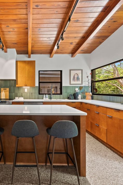 This Monaco Toffee kitchen by designer Travis blends our stained slab-style cabinets with a mix of knob and tab pulls. Terrazzo floors and a wood planked ceiling elevate the space, while vertically stacked green subway tile adds a bold pop of color. Kitchen Tile Mid Century Modern, Midcentury Modern Countertops, Mcm Green Kitchen, Mid Century Modern Kitchen Tile Backsplash, Mid Century Modern Walnut Kitchen, Wood Planked Ceiling, Green Backsplash Tile, Tile Mid Century Modern, Midcentury Kitchen Remodel