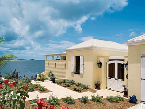 Pale yellow lightens up this already sun-drenched home, designed by architect Hortensia D. Lanio, on the waterfront of St. Croix. A beautiful juxtaposition against the deep blues of the Caribbean sky and sea, the sunny hue can also be found in the home’s interior, devised by Carlton Varney. Caribbean Style Homes, Caribbean House, Pastel Paint Colors, Dorothy Draper, Caribbean Homes, Caribbean Style, Traditional Exterior, St Croix, Tropical Houses