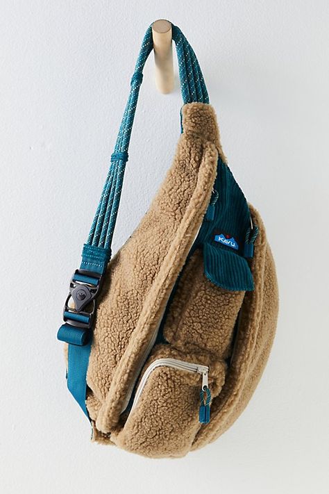 KAVU’s classic rope sling gets an ultra-cozy update! Featuring a soft sherpa fleece and slouchy silhouette, this functional bag is perfect for everyday use. **Features:** Soft sherpa fleece, cotton corduroy details, two vertical zip compartments, two key or cellphone pockets, padded back with embroidered detailing, adjustable 22" -44" rope shoulder strap with side-release buckle, elastic webbing keeper at strap end, 20" x 11" x 5" **Why We ❤️ It:** This slouchy sling is both fun and functional. Fleece Bag, Sporty Sunglasses, Wool Tights, Ruffled Socks, Blue Suede Shoes, Soft Headbands, Lace Gloves, Sports Prints, Hair Rings