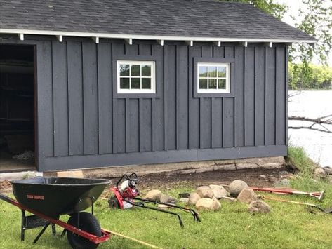 Board and batten siding using dark gray stained cedar boards on boathouse. Board And Batten Siding With White Windows, Grey Vertical Siding Exterior, Wood Board And Batten Exterior, Board And Batten Siding Black, Grey Board And Batten Exterior, Nice Garage, Stained Cedar, Black Shed, Diy Board And Batten