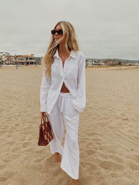 A woman dressed in a comfy and chic summer outfit barefoot at the beach. The button-up shirt and matching pant set is made of a textured soft cotton, and is worn half buttoned up for an effortlessly chic vibe. White Gauze Shirt Outfit, Gauze Shirt Outfit, Gauze Pants Outfit, Gauze Outfit, Summer Lounge Wear, Gauze Pants, 2024 Inspiration, Summer Lounge, Gauze Shirt