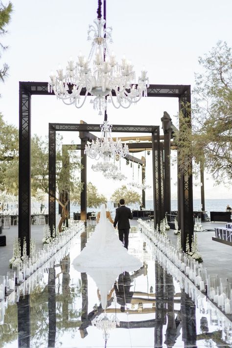 Newlyweds while walking down the aisle of their wedding venue. An aisle made of mirrors and decorated with plenty of candles, some white flowers and chandeliers. Classy Outside Wedding, Island Art And Taste Wedding, Monochromatic Wedding, Wedding Aisle Outdoor, Athens Riviera, White Wedding Ceremony, Monochrome Weddings, Black And White Wedding Theme, Hamptons Wedding