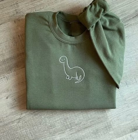 Embroidered dinosaur sweater 🦖 #dinosaur #embroidery #burnsyembroidery #cute Embroidered Dinosaur, Dinosaur Sweatshirt, Dinosaur Embroidery, Dinosaur Sweater, Embroidered Shirts, Dinosaur Activities, Sweatshirt Cute, Cute Dinosaur, Halloween Fashion