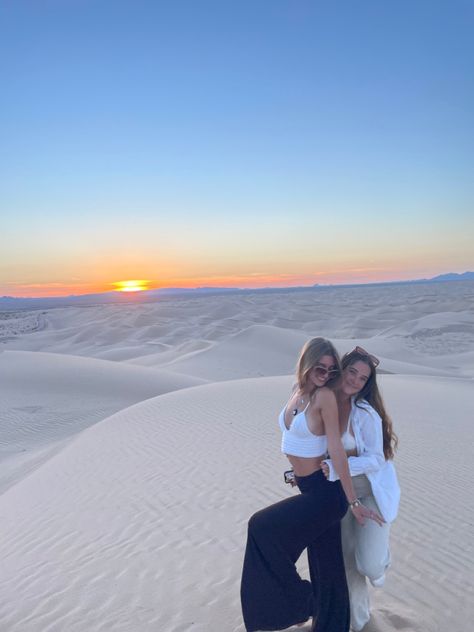 two girls at dan dunes at sunrise posing for the photo. one girl wears a while crochet top with float brown pants and the other wears a white button up Imperial Sand Dunes Photoshoot, Sand Dune Outfits, Hiking Trip Outfit, Dunes Pictures, Sand Dunes Aesthetic, Sand Dunes Outfit, Dunes Photoshoot, Imperial Sand Dunes, Lake Pics