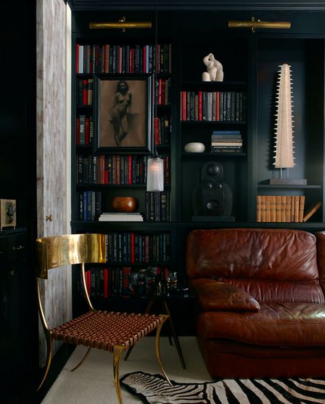 The Home Decor Essentials Every Modern Man Needs Mix of textures - worn leather, woven leather, brass, unfinished doors with black matte shelving. pinned by www.fioriinteriordesign.com Zigarren Lounges, Sofa Cognac, Klismos Chair, Masculine Interior, Library Wall, Dark Walls, Home Libraries, Dark Interiors, Built In Bookcase