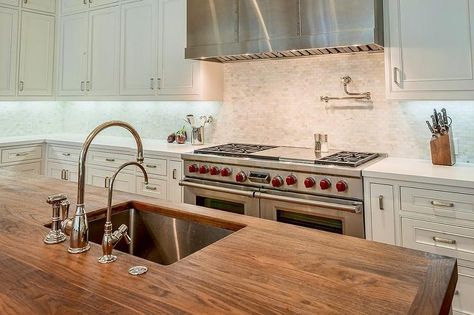 A butcher block kitchen island top holding an undermount stainless steel sink fitted with a gooseneck polished nickel faucet kit facing a Wolf dual range flanked by white shaker cabinets topped with white quartz countertops positioned against mosaic tumbled marble backsplash tiles holding a stainless steel hood above a polished nickel pot filler. Butcher Block Island With Sink, Butcher Block Island Top, Kitchen Island Top, Butcher Block Countertops Island, Kitchen Sink Undermount, Butcher Block Kitchen Island, Sink Undermount, Kitchen Island Tops, Butcher Block Island Kitchen