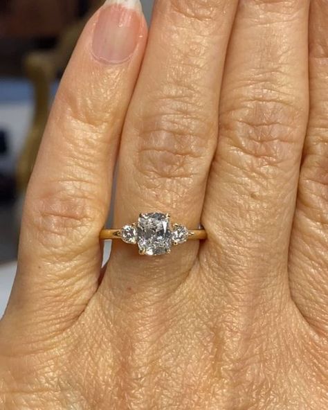 Cynthia Britt Custom Jewelry on Instagram: "A beautiful engagement ring for lovely Brenda! 🌟Story: Kathryn wanted a surprise engagement ring for Brenda. She had asked Brenda about her preferences so when time came, she asked her friends Scott and Kate, (I have created their engagement ring, wedding bands and a baby gift) for a recommendation and they referred me.  Kathryn knew Brenda liked an elongated cushion cut diamond preferably in a three stone ring. She was open to suggestions for both the center diamond and the style of the ring.  I first brought her a few diamonds to pick from and she chose an amazingly cut cushion brilliant cut diamond. Based on her chosen diamond and Brenda's hand structure and personal style, I recommended one round brilliant cut diamond on either side of the 3 Stone Elongated Cushion Engagement Ring, Unique Three Stone Engagement Rings, Elongated Cushion With Side Stones, Cushion Cut Three Stone Engagement Ring, Three Stone Cushion Engagement Rings, Elongated Cushion Three Stone, Three Diamond Engagement Rings, Hand Structure, Engagement Ring Elongated Cushion