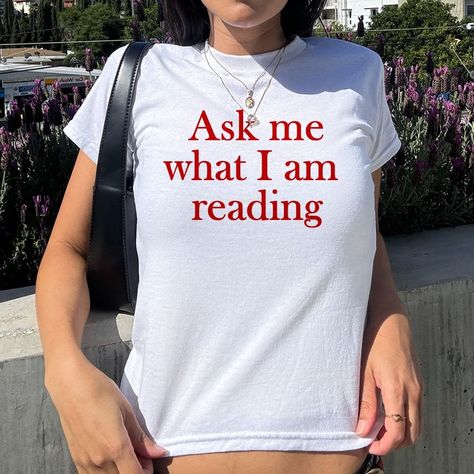 This Ask Me What I am Reading Baby Tee is the perfect addition to any book lover’s wardrobe. With its trendy aesthetic and comfortable fit, it's great for women of all ages. Show off your love for books while looking stylish and effortlessly cool. A ... #printwithsky #streetwear #trendytop #GraphicTee #BabyTee #pinterestinspired #londonstyle #lafashion #nycstyle #nycfashion #summeroutfit #90sfashion #90sbabes #pinterestgirl #whatiworetoday #dailyfashion Book Outfit Aesthetic, Book Tshirts Ideas, Lover Aestethic, Funny Graphic Tees For Women, Bookworm Outfits, Indie Shirts, Baby Tee Aesthetic, Graphic Tee Aesthetic, Reading Tshirt