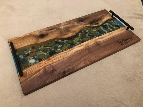 Black walnut river rock boards Available in 18”x10” & 24”x12” Translucent base and blue base options #charcuterie #charcuterieboard #servingboard #giftideas #unique #oneofakind #handcrafted #madeincanada #orangeville #ontario #blackwalnut #epoxyresin #riverstone Shelf Wood, River Stones, River Rock, Wood Products, Top Shelf, Black Walnuts, Serving Board, Black Walnut, Charcuterie Board