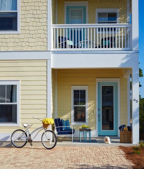 Side view of a yellow two story house with a turquoise blue front door under a second level balcony. Yellow Beach House, Yellow House Exterior, Paint Trim, Turquoise Door, Cream Kitchen, Beach House Exterior, Seaside Living, House Of Turquoise, Cottage Exterior