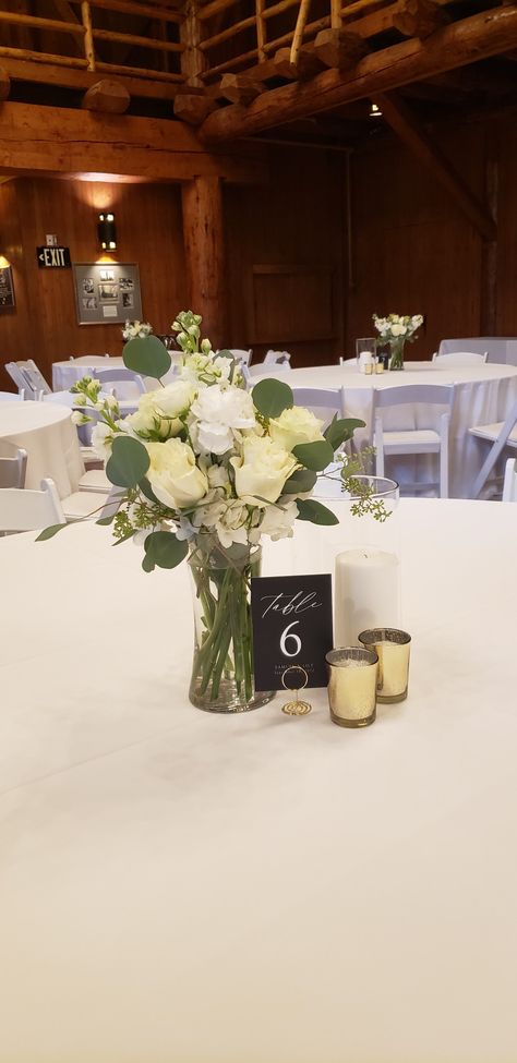 Mixed white and green centerpiece in 8 inch tall vase Simple Wedding Centrepieces Round Tables, White Roses Table Centrepiece, Eucalyptus And Rose Centerpiece, White Rose And Eucalyptus Centerpiece, Simple White Rose Centerpiece, Roses And Eucalyptus Centerpiece, Simple White Flower Centerpieces, Small Vases Centerpiece Wedding, Simple Rose Centerpiece