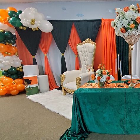 Step into a vibrant indoor birthday setting that radiates joy! Behold a large adjustable metal arch, elegantly draped with white, black, gold, and orange sheer organza curtains. Adorned with a delightful garland of white, orange, and emerald green latex balloons, it creates a striking backdrop. An orange table runner complements a luxurious emerald green velvet tablecloth, inviting guests to a feast fit for royalty. The centerpiece steals the show with faux silk flowers arranged in a tall gold m Green Velvet Tablecloth, Orange And Emerald Green, Organza Curtains, Birthday Setting, Photo Backdrop Stand, Velvet Tablecloth, Event Decor Ideas, Party Decorations Table, Flowers Balloons