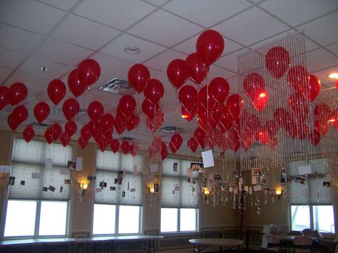 balloons on the ceiling over a dance floor with photos of the guest of honor through the years. Balloons Hanging From Ceiling Upside Down, Helium Balloons Ceiling, Ceiling Full Of Balloons, Led Balloons Hanging From Ceiling, Balloon Dance, Ballon’s Hanging From Ceiling, Balloon Ceiling, Red Balloon, Bedroom Flooring