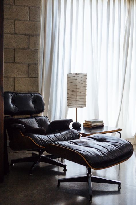 Warm corner featuring black leather Eames lounge chair and ottoman, sheer curtains, exposed brick walls, concrete floors and a mod side table | Photos by Laure Joliet for Remodelista Lounge Chair Bedroom, Chic Loft, Lounge Chair And Ottoman, Attic Flooring, Attic Renovation, Cozy Chair, Attic Bedroom, Design Apartment, Attic Rooms