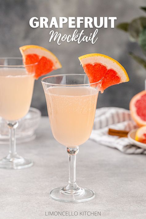 Side view of two Grapefruit Mocktails in goblet style wine glasses on a gray countertop, each with a quarter slice of grapefruit as a garnish on the rim of the glass. Cut fresh pink grapefruit is in the background on the right along with a gray striped linen, cinnamon sticks and some greenery in a vase. Text above the drinks reads “Grapefruit Mocktail”. Grapefruit Mocktail, Flavor Pairing, Citrus Drinks, Non Alcoholic Punch, Cinnamon Syrup, Brunch Drinks, Dry January, Mocktail Recipe, Grapefruit Juice