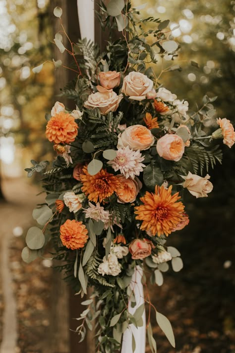 This photo features an outdoor wooden wedding ceremony arch. The right side of the arch has a fresh floral arrangement in the colors blush and orange with some accents of greenery. The flowers are mums, dahlias and roses and the greenery is eucalyptus and leatherleaf. Fall Wedding Aisle Decor, Fall Wedding Aisle, Arch Florals, Wedding Aisle Decor, Mountains Wedding, Wedding Ceremony Arch, Wedding Aisle Decorations, Boquette Flowers, Flower Business