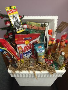 Male gift basket. A great idea for the outdoorsman!   Styrofoam cooler, fishing magazine, potato chips, meat sticks, candy bars, sunflower seeds, mini liquor bottles, grilling utensils, fishing bobbers And assorted tackle. Gone Fishing Gift Basket Ideas, Fishing Gift Basket Ideas Diy, Fathers Day Fishing Gift Basket, Fish Themed Gift Basket, Father's Day Basket Ideas, Fishing Easter Basket For Men, Fisherman Gift Basket, Male Gift Baskets, Father’s Day Gift Baskets