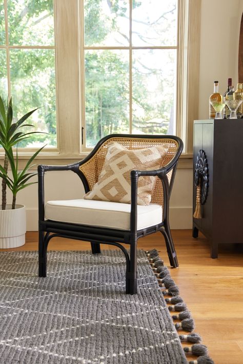 Handcrafted in Indonesia, the Lisette Black Rattan & Honey Cane Chair features a curved cane back and an ivory seat cushion with a herringbone pattern. The warm texture of the cane-woven back contrasts beautifully with the matte-black frame's rounded curves and wrapped joints. Pitched at the perfect angle for lounging and always cozy with its plush cushion, this contemporary two-tone armchair is a prime seat for any space. #WorldMarket #RattanChair #LucianoLiving #HomeDecor #LivingRoomDecor Cane Barrel Chair, Rattan Chair Living Room, Cane Accent Chair, Papasan Chair Frame, Blue Upholstered Chair, 2023 Highlights, Traditional Accent Chair, Unique Living Room Furniture, Pine Dining Chairs