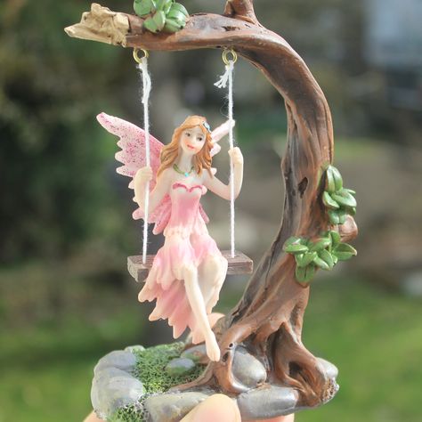 This beautiful, swinging fairy statue made of resin is a must-have addition to any home seeking magic and charm.  The statue depicts a fairy swinging on a tree branch, carried by the gentle breezes. Each movement causes the fairy to gently sway back and forth, lending a calming atmosphere to the room.  This decorative figure is a true work of art and is sure to enchant every visitor.  Place it on a shelf or table to make your home a place full of magic! Material: Resin Size: 14x10 cm (5,5x3,9") Magical Home Decor, Sway Back, Garden Fairies Figurines, Antique Porcelain Dolls, Fairy Statues, Magical Home, Resin Statue, Fairy Aesthetic, Calming Atmosphere