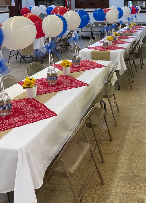 White table cloths, red bandanas, balloons on sticks tied together with blue tulle, mason jars with blue checkered ribbon, burlap table runner, sunflowers in white pots. Western Table Decorations, Balloons On Sticks, Cowboy Themed Birthday Party, Western Table, White Pots, Cowboy Theme Party, Western Birthday Party, Wild West Party, Rodeo Party