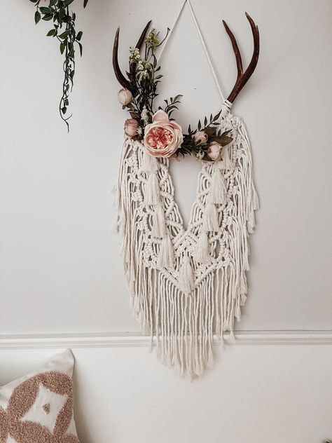 Florals adorn an intricate macrame wall hanging on a set of deer antlers. Made with 100% cotton cord Boho Theme Bedroom Decor, Boho Deer Antlers Decor, Macrame Deer Antlers Wall Hangings, Crafts With Antlers Diy, Hanging Antlers On Wall, Macrame Antler Diy, Deer Horn Macrame, Boho Antler Decor, Macrame With Deer Antlers