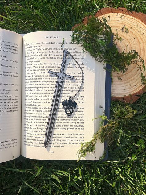 Leather Sword Bookmark, Fantasy Bookmark, Elven-Inspired Bookmark, Gift for Readers, Elf Fairy Faerie Fae Bookmark Make your reading a little extra magical with this beautiful engraved faux leather bookmark with a metal dragon tassel. This bookmark is engraved in my home workshop on faux leather leatherette that engraves into a light silver color and finished with a metal dragon charm. HANDCRAFTED IN THE USA- Made in Los Angeles, California by a small, family-owned business NATURAL VARIATION DIS Faux Leather Bookmark, Bookmark Holder, Fantasy Bookmarks, Dragon Bookmark, Metal Dragon, Elf Fairy, Pretty Knives, Creative Bookmarks, Fantasy Props