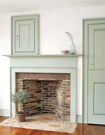 Pale Soft Green Paint used on the Fireplace Wood  Surround and Doors. A potted Topiary dresses the Hearth and a Blue Tint Bottle with a Feather dresses the Mantle. Colonial Home Renovation, Soft Green Paint, Greek Interior, Fireplace Apartment, Foster House, Fireplace Doors, Paint Fireplace, Old Fireplace, Farmhouse Fireplace