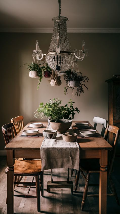 Step into a warm and inviting dining space featuring a stunning farmhouse dining table at its heart. Surrounded by mismatched wooden chairs, this setup exudes rustic charm and communal vibes. A soft linen table runner adds texture, while beautiful ceramic dinnerware sets the stage for memorable meals. Don't miss the eye-catching cluster of hanging planters that brings life to the atmosphere, complemented by a dramatic chandelier casting a gentle glow. Ready to elevate your dining experience? Discover how to create this cozy setup in your home! #FarmhouseStyle #DiningRoomInspo #HomeDecor Hygge Dining Room, Farmhouse Dining Area, Dramatic Chandelier, Cozy Setup, House Dining Room, Dining Room Cozy, Charming Farmhouse, Ceramic Dinnerware Set, Wooden Chairs