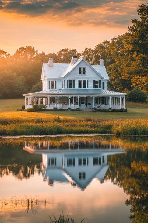 White farmhouse with large wraparound porch large pond with reflection of the house in front sunset scene scenic farmland landscape. The whimsical allure of countryside houses makes these charming abodes more than just a roof and four walls amidst the rolling hills and chattering wildlife. House With Wrap Around Porch Farmhouse, Ranch House With Wrap Around Porch, House With Big Yard, Upstate Farmhouse, Wraparound Porch Farmhouse, Wrap Around Porch Farmhouse, Wrap Around Porch House Plans, Farm Mansion, Farmhouse With Wrap Around Porch