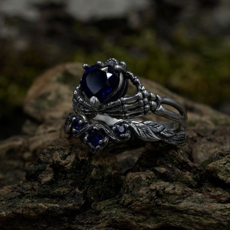 Crafted from sterling silver, our Gothic Wedding Ring Set with Sapphire is a bewitching ensemble that embodies the mystique of a dark elven fairy realm. The set includes unique stack rings with intricate details such as a sapphire heart, chevron, and twig and leaf motifs, creating a fantasy forest aesthetic. Perfect for those with a penchant for witchy and gothic styles, this unique jewelry set symbolizes the enigmatic charm of the woodland. Characteristics: Metal - Recycled solid sterling silve Fantasy Wedding Ring Set, Gothic Wedding Rings Set, Gothic Fantasy Wedding, Engagement Rings Dark, Gothic Wedding Bands, Fantasy Forest Wedding, Witchy Wedding Rings, Dark Wedding Rings, Dark Fantasy Wedding