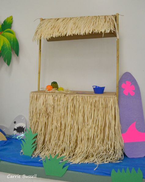 Tiki hut luau decoration. Cost less than $5. Large cardboard box, 3 grass skirts hot glued on, 2 bamboo poles from the garden section and some twine. Surfboard made from cardboard and covered in paper. Surf Shack Vbs, Skirts Hot, Garden Section, Vacation Bible School Themes, Large Cardboard Boxes, Luau Decorations, Aloha Party, Hawaiian Luau Party, Luau Birthday Party