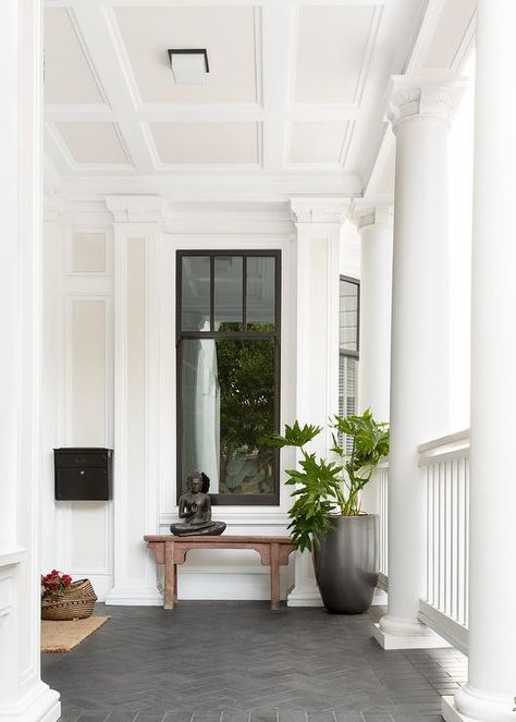 Transitional porch with dark gray herringbone pattern floor pavers furnished with a chinoiserie bench under a window beside a tall black planter. White Rocking Chairs, Front Door Lighting, White Porch, White Siding, Porch Tile, Teak Flooring, Pacific Heights, Mediterranean Style Homes, White Shiplap