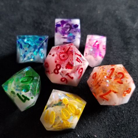 This set of dice features recycled resin scraps cut into small pieces and combines with glitter and colored resin to create a rainbow of dice. Resin Dice Ideas, Dice Inspiration, Diy Resin Dice, Goblin Hoard, Dice Ideas, Cool Dnd Dice, Dnd Journal, Pretty Dice, Dice Dragon