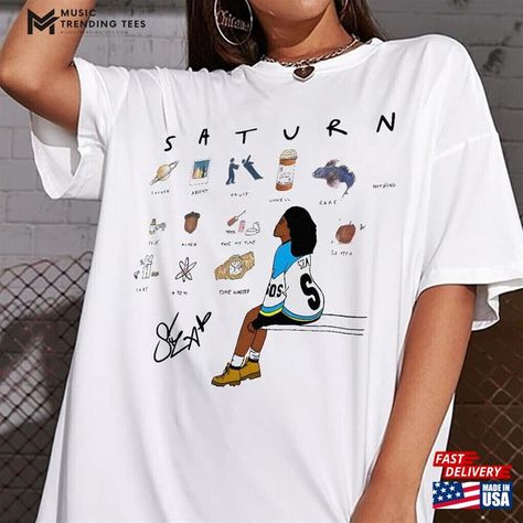 Sza Saturn Unisex T-Shirt White 2024 New Release Music Fan Tee Single Sweatshirt Hoodie Check more at https://musictrendingtees.com/product/sza-saturn-unisex-t-shirt-white-2024-new-release-music-fan-tee-single-sweatshirt-hoodie/ 90s Shirts Graphic Tees, Sza Singer, Shirt Designs For Men, Iconic Album Covers, 90s Shirts, Music Fans, Quality T Shirts, Branded T Shirts, Diy Clothes