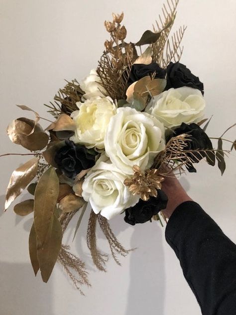 If your theme is gold and you are not superstitious about black, then this is a gorgeous, simple unstructured yet round bouquet for you.  This bouquet is high end quality  black roses, cream latex David Austin, realistic roses, dried and sprayed gum leaves, grevillea &  sprayed in a gorgeous gold.  This listing is for 1 Bridal bouquet and 1 Groom button hole. See one of our beautiful Brides, Jayme who ordered this gorgeous creation.  I can custom order to suit, simply send me a message. For over Gold Wedding Bouquets, Gold Wedding Flowers, Black Bouquet, Gold Bouquet, Gum Leaves, Black And White Wedding Theme, Round Bouquet, Black Gold Wedding, White Wedding Theme