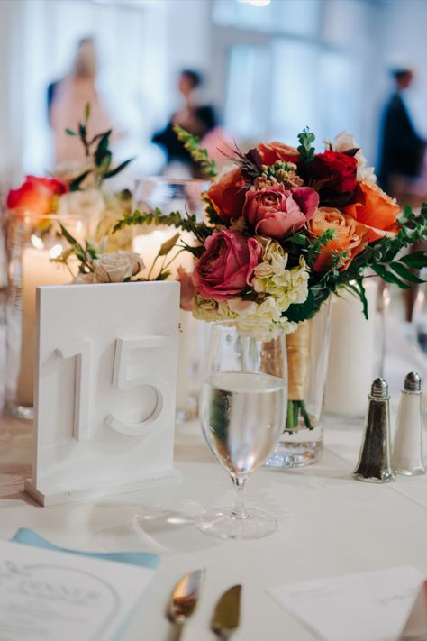 Colorful bridesmaid bouquet re-purposed as centerpiece. PC Tyler Boye https://tylerboye.com/ Repurposed Bouquet Centerpiece, Repurposed Bridesmaid Bouquet Centerpiece, Bridesmaid Bouquet Centerpiece, Bouquet Centerpiece, Candle Centerpiece, Candle Centerpieces, Bridesmaid Bouquet, Table Numbers, Wedding Centerpieces