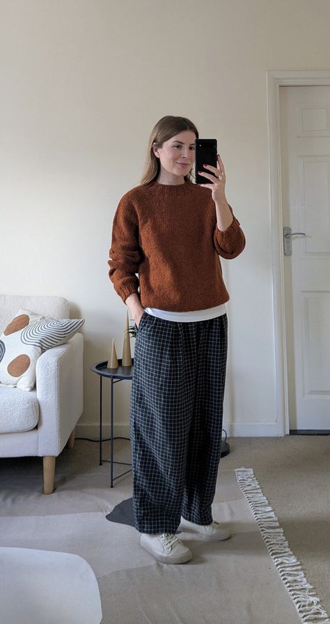 A woman stands in front of a mirror. She wears a burnt orange jumper on top of a white t-shirt, navy and white checked trousers and white canvas sneakers. Winter Jumper Outfit, Check Trousers, Winter Jumpers, Knitwear Outfit, Jumper Outfit, Checked Trousers, Burnt Sienna, Wool Jumper, Sweater Outfit