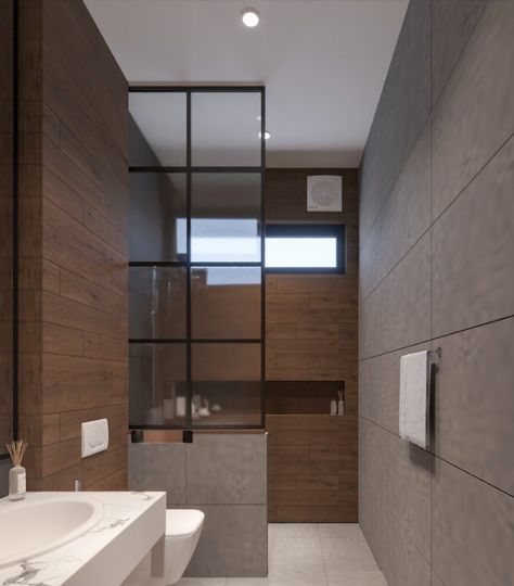 This stunning small bathroom design has a very modern yet minimalist vibe. A tall mirror is mounted on the wall and is accompanied by a small vanity. The shower area has been cleverly separated from the rest of the space by a glass partition, resting on a small wall, acting as a barrier. The shower area features a narrow yet wide niche, which is perfect for storing shower products, adding to the functionality of the space. Shower Area Glass Partition, Bathroom Shower Partition Wall, Narrow Bathroom Design Ideas, Bathroom Glass Partition Ideas, Small Bathroom Partition Ideas, Bathroom Partition Glass Design, Small Toilet Design Modern Minimalist, Wash Room Ideas Bathroom, Washroom Glass Partition