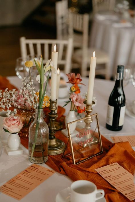 Round tables for wedding reception with orange table runners and orange wedding menus with white candles, glass vases of flowers and a clear gold photo frame table name Photo Frame Table, Round Table Centerpieces, Round Wedding Tables, Round Table Decor, Yellow Wedding Flowers, Ireland Wedding, Wedding Table Flowers, Table Runners Wedding, Orange Wedding