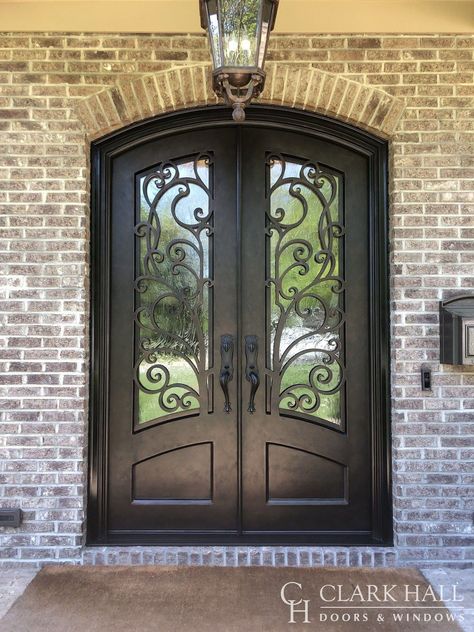 The ornate style of these custom wrought iron double entry doors transforms the entire design of the home’s front entrance. Crafted with a grand arch, obscure glass, and ornate details, these bronzed iron exterior doors demand attention. Fancy Front Door Entrance, Iron Entry Doors Double, Two Door Entrance Front Entry, Ornate Front Door, Iron Front Door Double, Double Entry Front Doors, Wrought Iron Doors Front Entrances, Wrought Iron Entry Doors, Wrought Iron Front Door