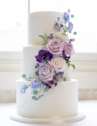 Wedding Cake Inspiration | Norfolk | Love Wedding Cakes Purple Wedding Cake Ideas Lavender, Navy Blue And Lavender Wedding Cake, Pastel Wedding Cake Flowers, Purple Blue Wedding Cake, Wedding Cake Light Purple, Purple Floral Wedding Cake, Light Purple Wedding Cake, Blue And Purple Wedding Cake, Lilac And Blue Wedding