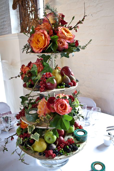 Flowers and fruit wedding table centre, cup cake stand in hot colours ideal for the summer wedding. Fruit On Cake Stand, Fruit Table Ideas Wedding, Fruit Table Wedding, Autumnal Cake, Fruit Flower Arrangements, Fruit Display Wedding, Flowers Display, Autumn Fruit, Fruit Table