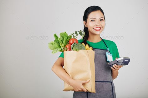 Young female supermarket worker by DragonImages. Pretty smiling young female supermarket worker holding paper package with food and payment therminal #Sponsored #DragonImages, #Pretty, #smiling, #worker Holding Paper, Dragon Images, Travel