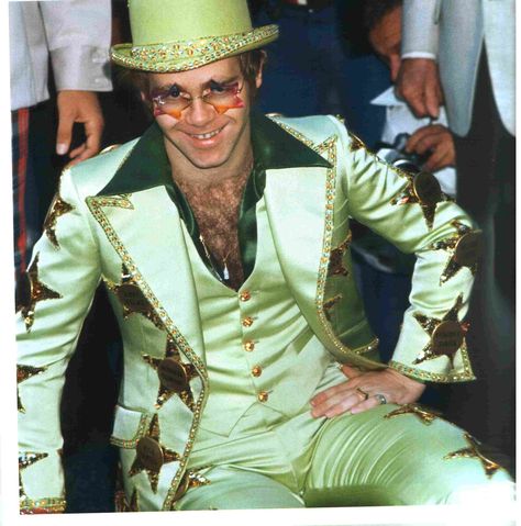 This is a color photo of Elton John receiving his Star on the walk of fame in Hollywood, California October 24,1975 Notice that his suit is a lime green but in another photo on this board, you will find that it is gold. I believe this photo may be more accurate. Elton John Outfits, Elton John Costume, Fred Mercury, Look Disco, Feather Outfit, David Furnish, John Barry, Jamie Bell, Iconic Outfits