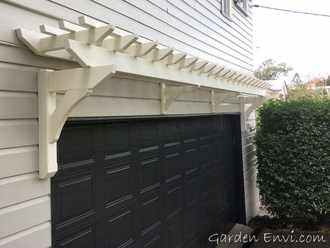 This small white Eyebrow Pergola creates a focal point above the garage door softening the exterior of the side of the house.   With no visible fixings it makes a great features for this Queenslander residence in Indooroopilly, Brisbane. #hamtponsstyle #hamptonsperogla #queenslanderhouses Eyebrow Pergola Garage Doors, Garage Eyebrow Pergola, Garage Eyebrow, Pergola Over Garage, Eyebrow Pergola, Garage Arbor, Rock Exterior, Door Portico, Garage Trellis