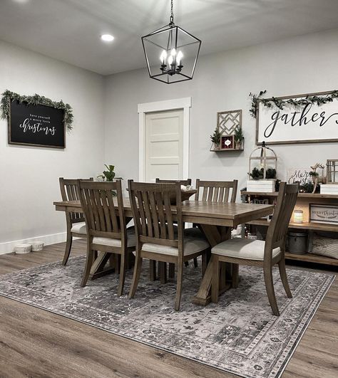 Stained wood X base dining table is lit by a black lantern pendant light in this farmhouse dining room with gray walls. The table is accompanied by matching stained wood dining chairs with white seat cushions. Dining Rooms With Farmhouse Chandeliers, Modern Rustic Home Decor Ideas, Dinning Room Modern Farmhouse Decor, Dining Room With Grey Walls, Black Farmhouse Kitchen Decor, All White Home Decor, How To Decorate A Dining Room Wall, Small Kitchen Theme Ideas, Dining Room Themes