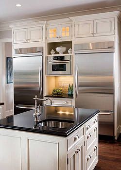 Opposite the sink wall, two 36-inch stainless steel refrigerators flank a built-in microwave. To tie in with the home’s traditional crown molding, Berkemeyer topped the cabinets with detailing that echoes it. Lighted glass fronts in the center section of the upper area give a warm glow.   - ELLEDecor.com Traditional Crown Molding, Outdoor Kitchen Appliances, Built In Refrigerator, Kitchen Refrigerator, Kitchen Redo, Crown Molding, Kitchen Remodel Idea, Kitchen Layout, Side By Side