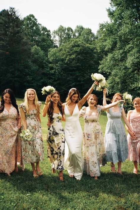 bride holding bouquet in the air with bridesmaids in floral dresses around her Spring Wedding Bridesmaids Dresses, Floral Bridesmaid Dresses Mismatched, Bridesmaid Dresses Floral, Bridesmaid Dresses 2024, Bridesmaid Dresses Different Colors, Spring Wedding Bridesmaids, Nude Bridesmaid Dresses, Wedding Bridesmaids Dresses, Dream Garden Wedding